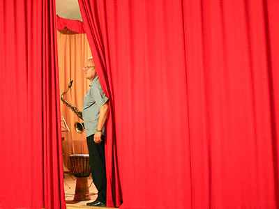Ein Musiker am halb geöffneten Vorhang auf der Bühne
