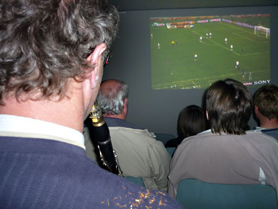 Uwe Loda mit Klarinette von hinten. Leinwand mit Spiel.
