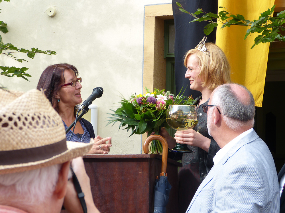 Anne Kloos übergibt einen Blumenstrauß an die Weinkömigin